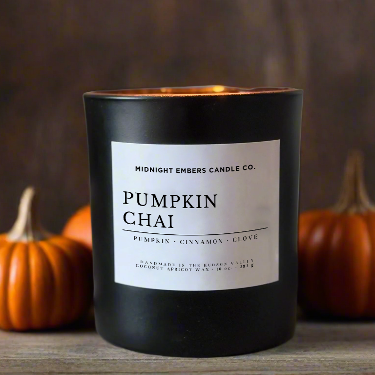 Candle labeled 'Pumpkin Chai' with pumpkins and twigs in the background