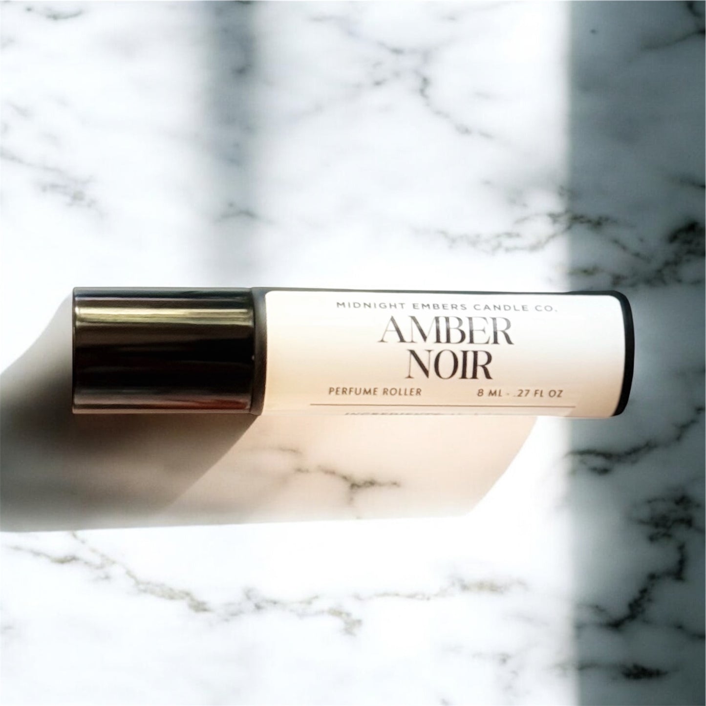 Perfume roller labeled 'Amber Noir' on a marble background