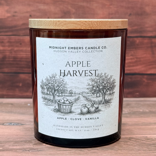 Candle labeled 'Apple Harvest' from Midnight Embers Candle Co. on a wooden surface.