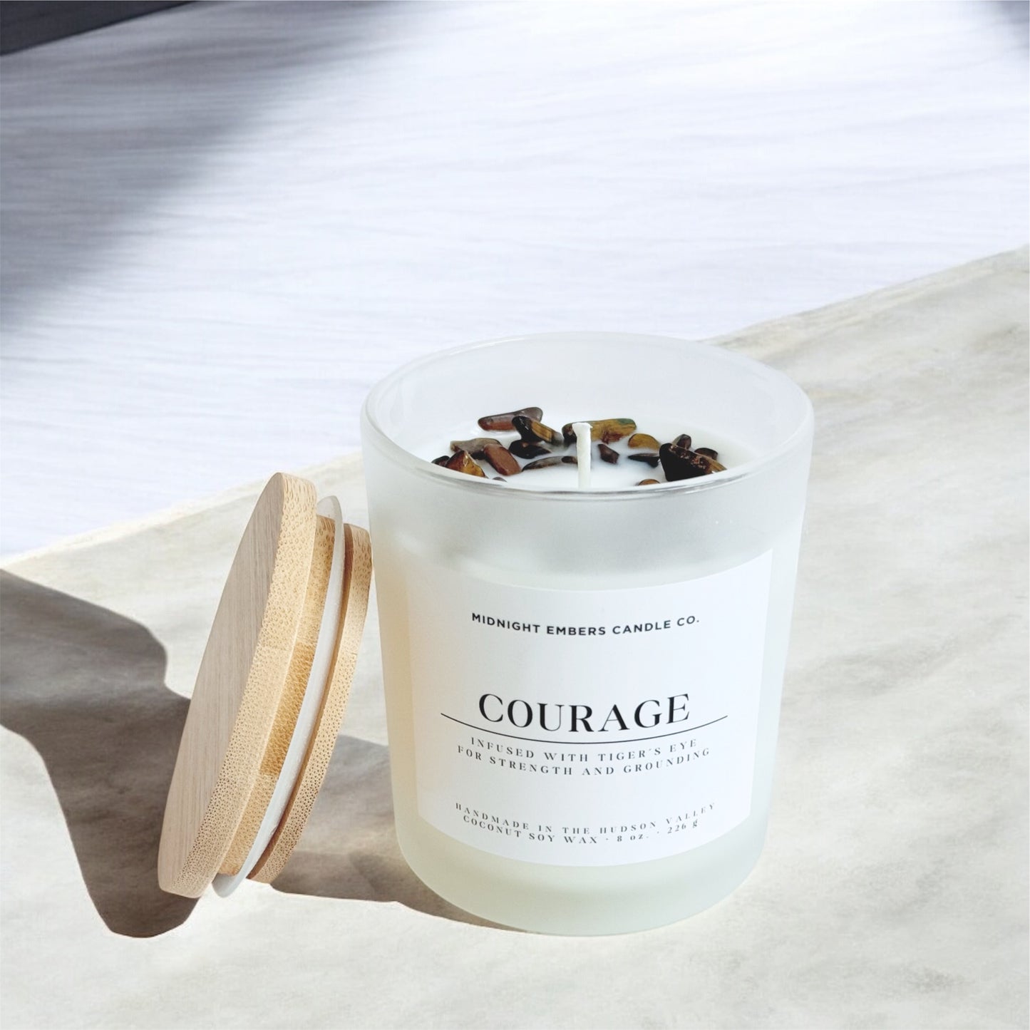 Candle labeled 'Courage' by Midnight Embers Candle Co. on a white surface.
