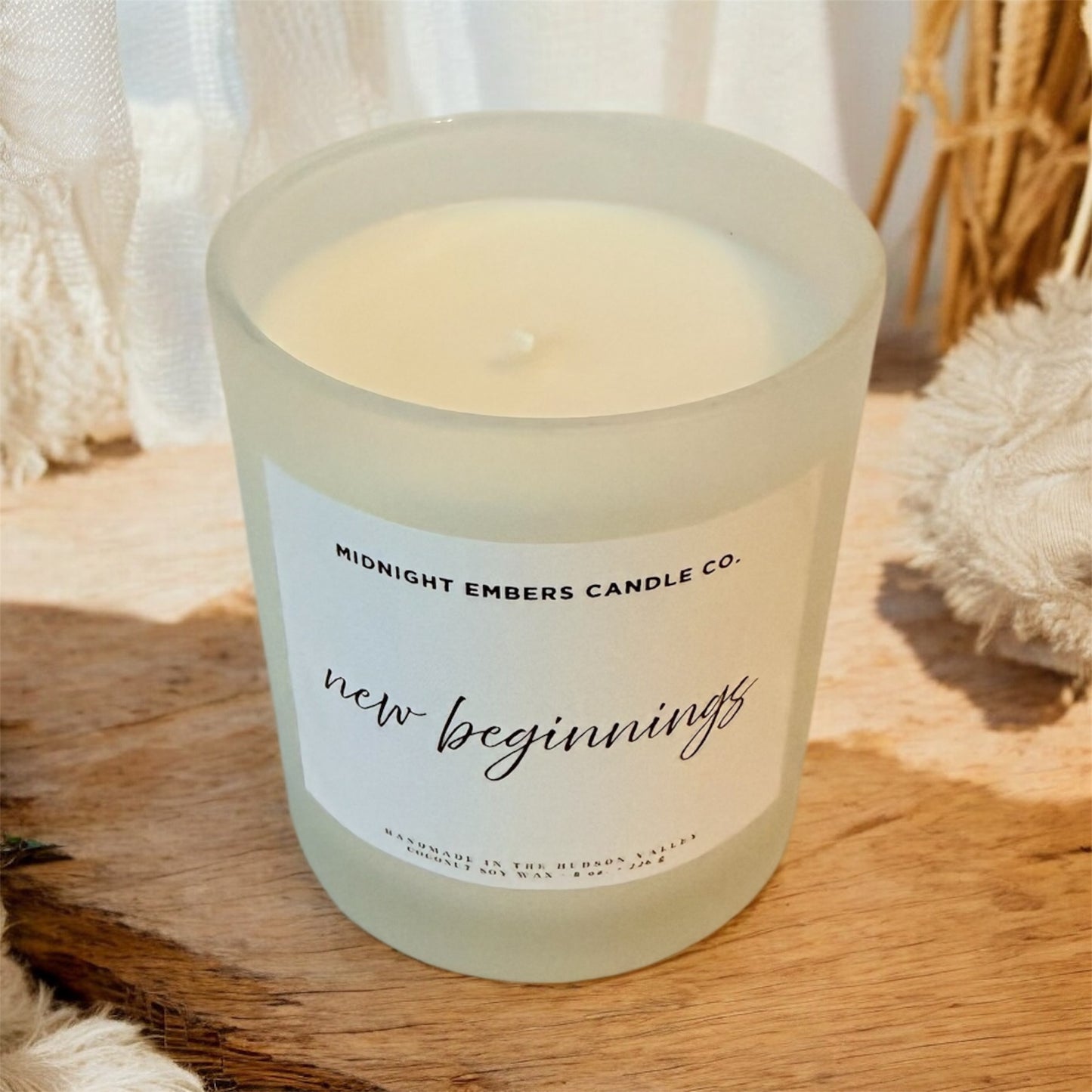 Candle with 'Midnight Embers Candle Co.' label on a wooden surface