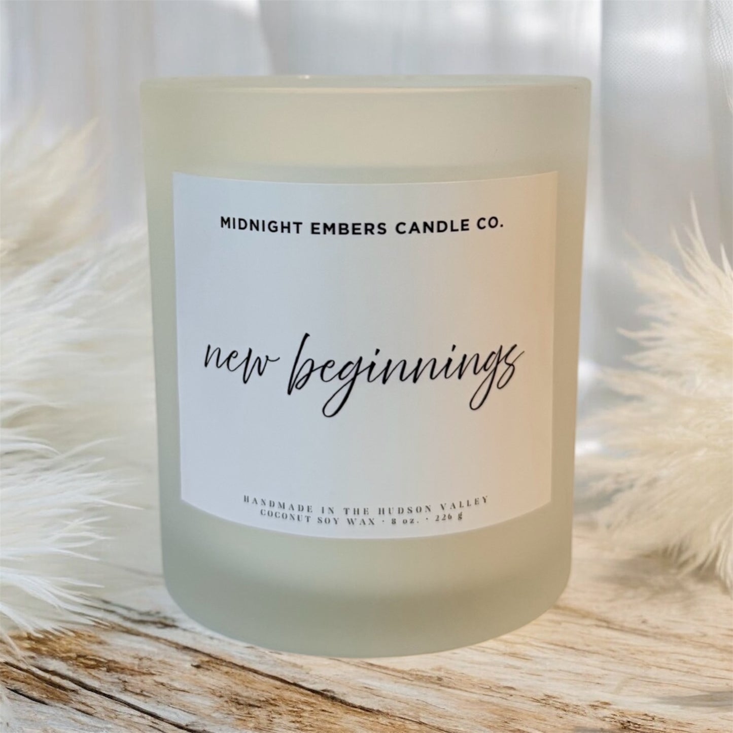 Candle with 'New Beginnings' label by Midnight Embers Candle Co. on a soft white background.