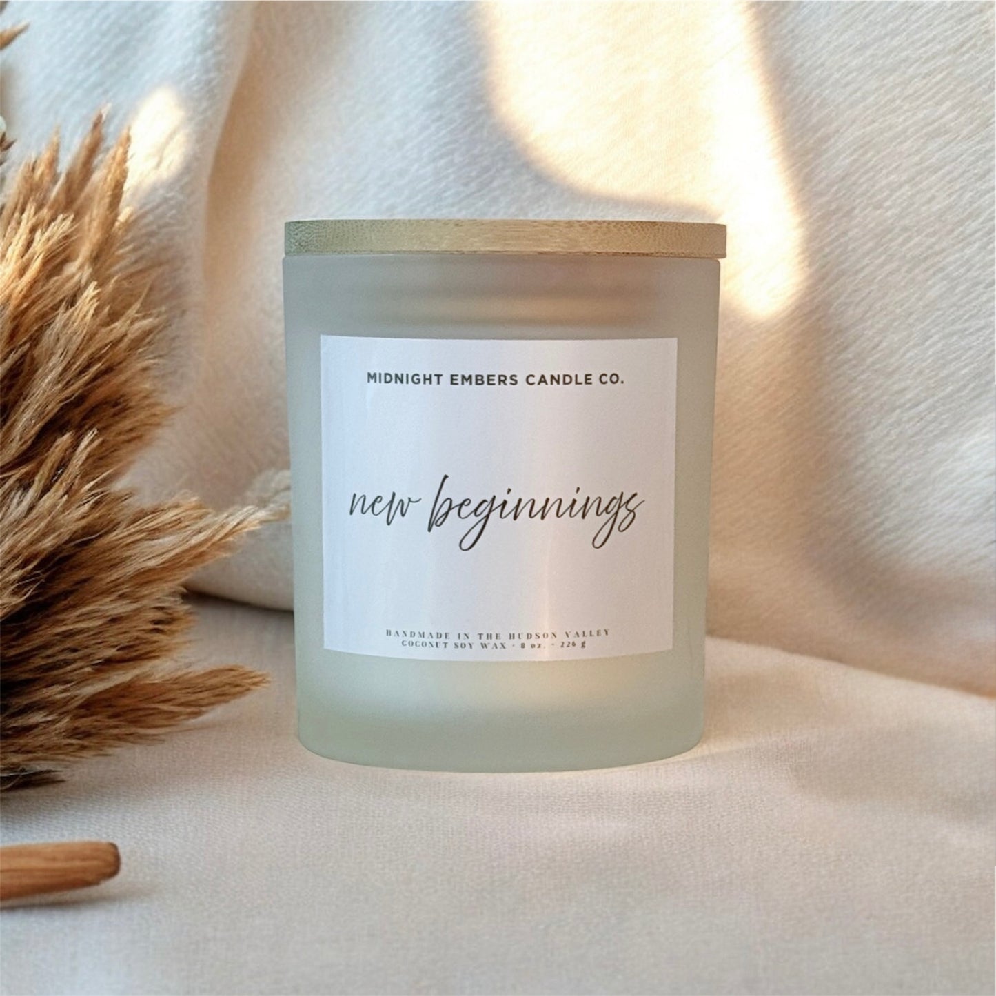 Candle with 'new beginnings' label on a soft background