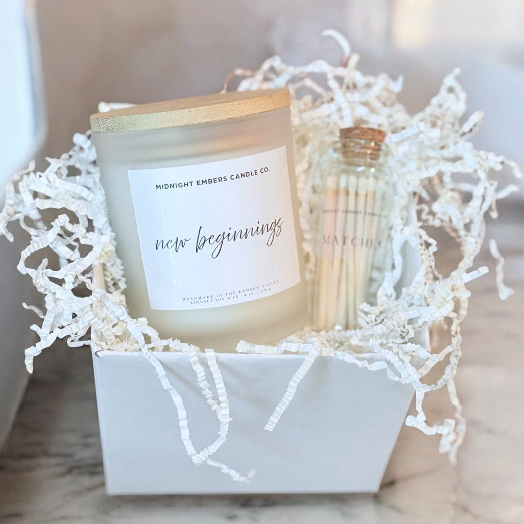 Candle in a decorative box with white shreds on a marble surface
