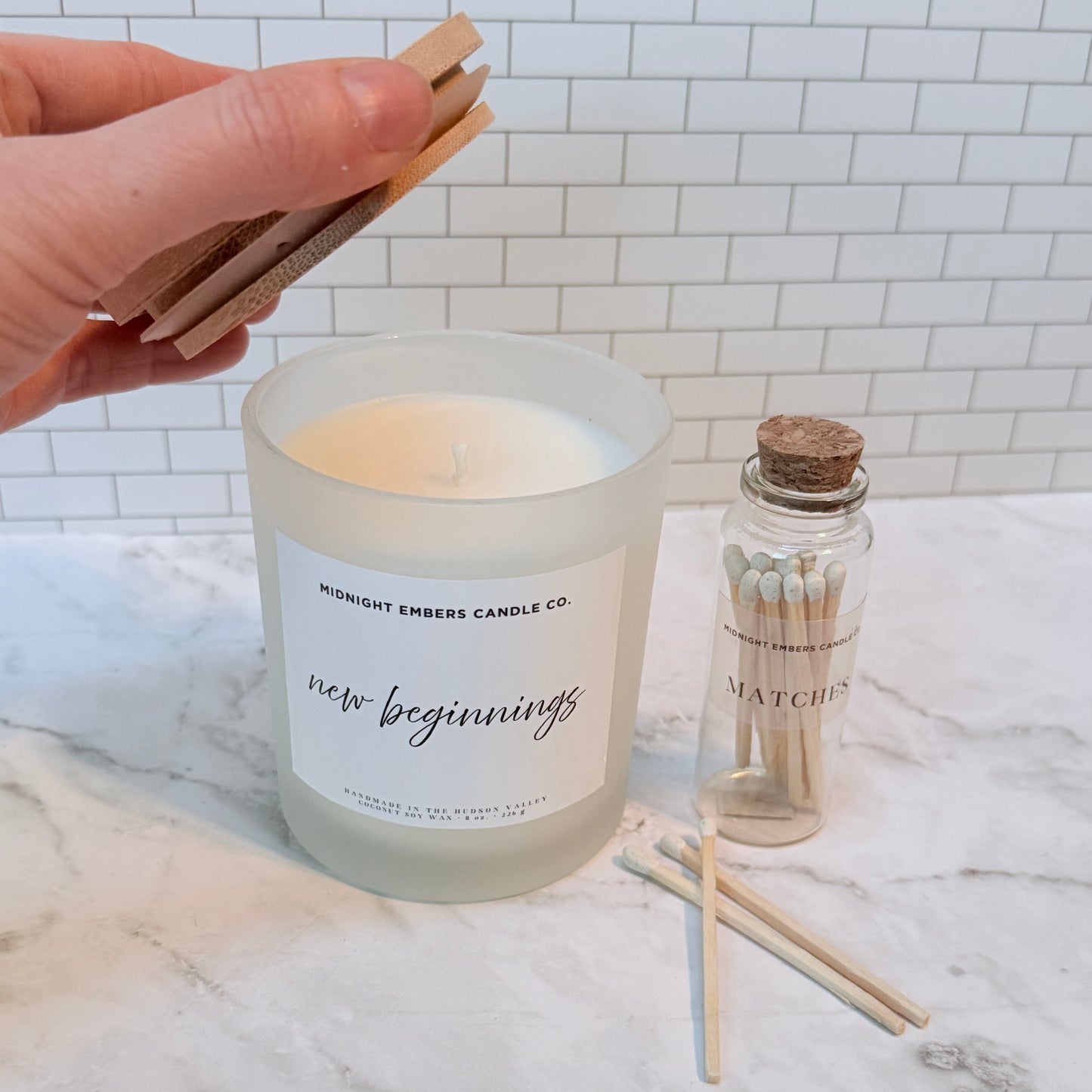 Candle labeled 'New Beginnings' with matches on a marble surface