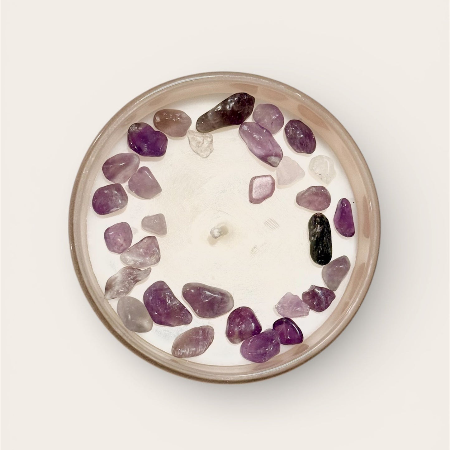 Candle with embedded purple and clear stones on a white background