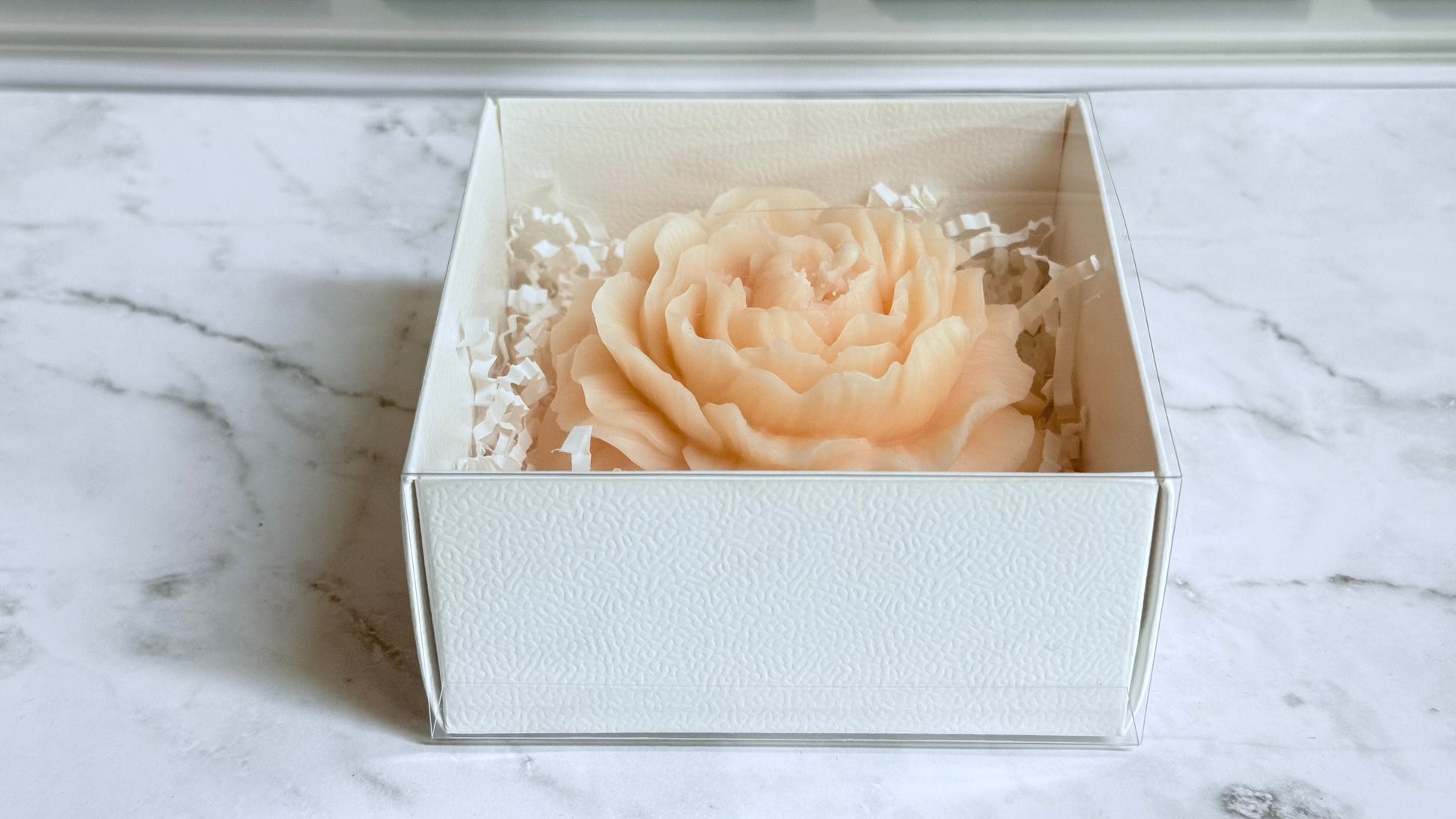 White box with a decorative peony on a marble surface