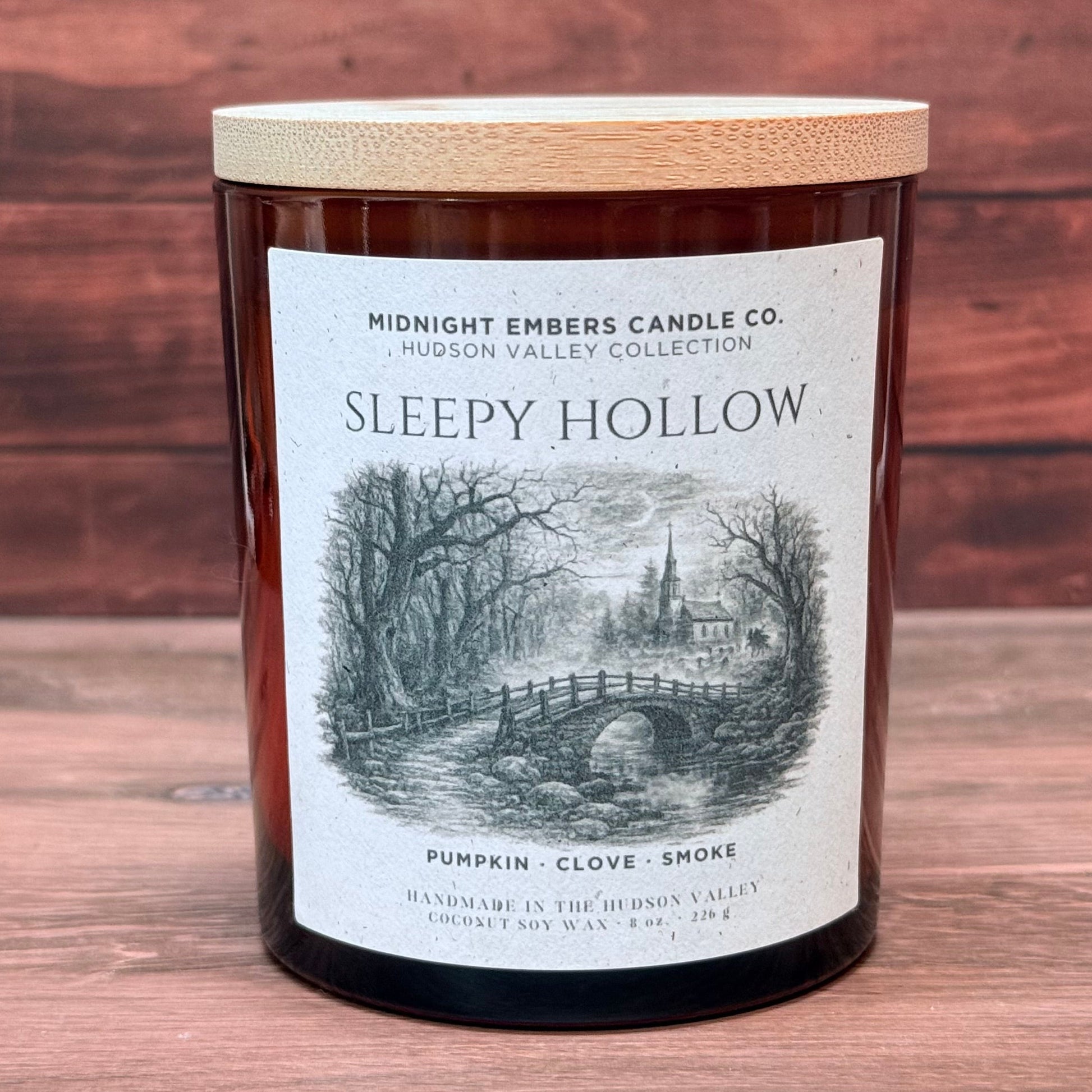 Candle labeled 'Sleepy Hollow' with a wooden lid on a wooden surface.