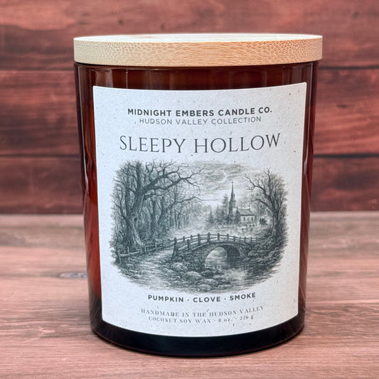 Candle labeled 'Sleepy Hollow' with a wooden lid on a wooden surface.