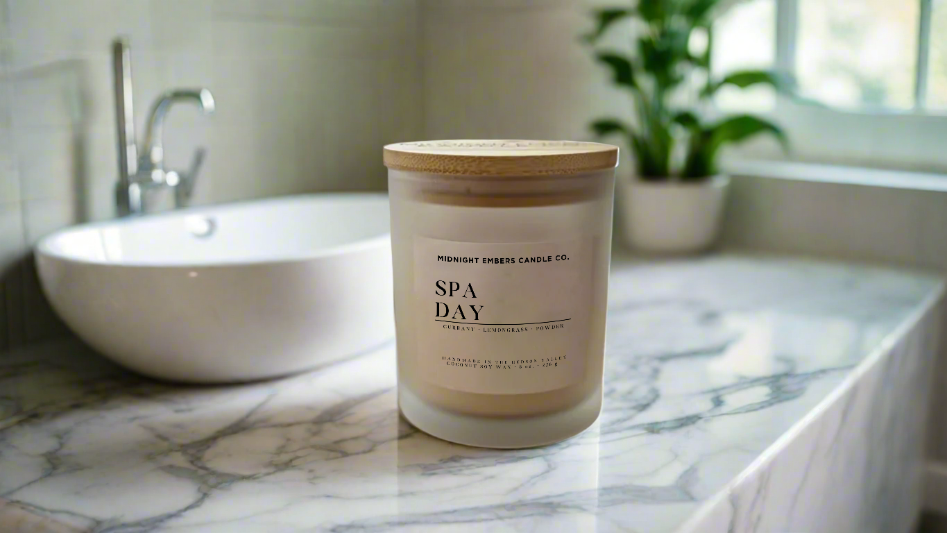 Candle labeled 'Spa Day' on a marble countertop with a bathroom setting.