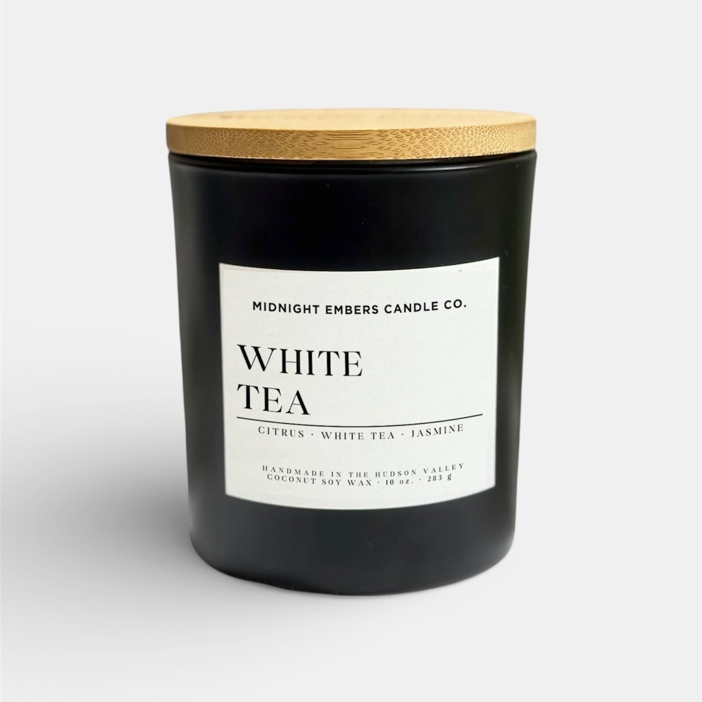 Black candle with a wooden lid labeled 'White Tea' by Midnight Embers Candle Co. on a white background.
