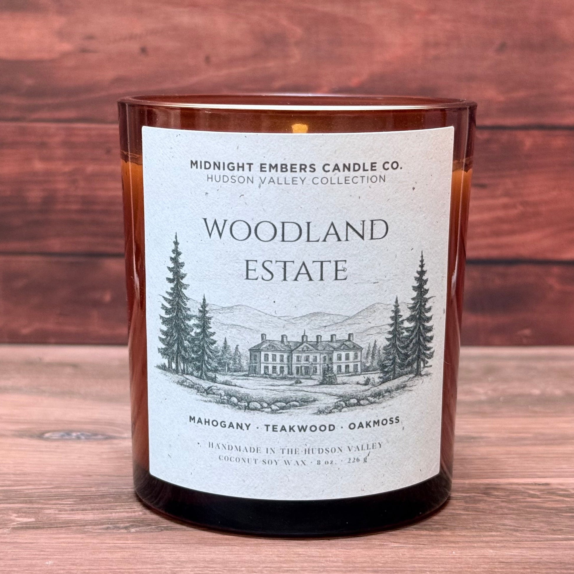Candle with 'Woodland Estate' label on a wooden surface