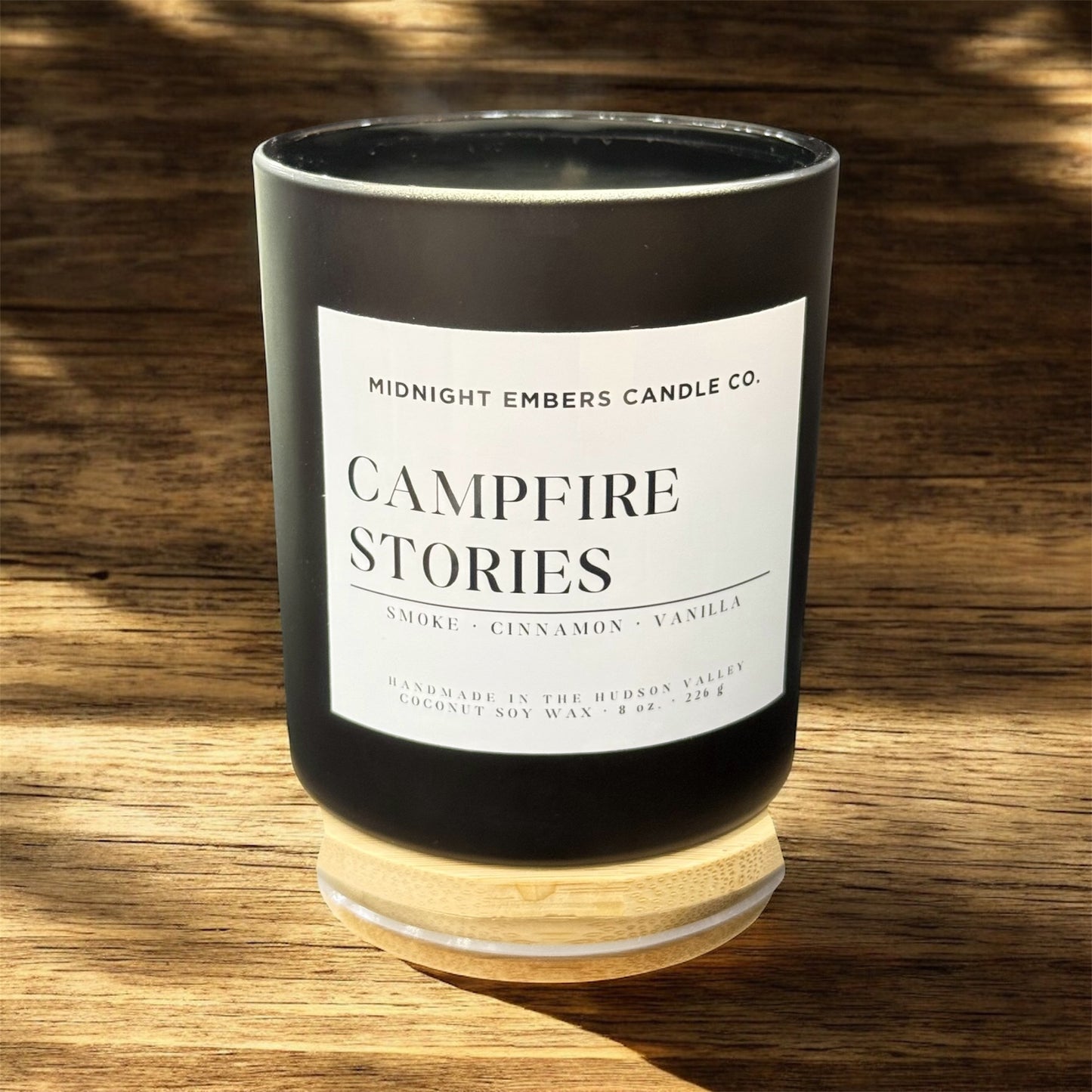 Candle with 'Campfire Stories' label on a wooden surface