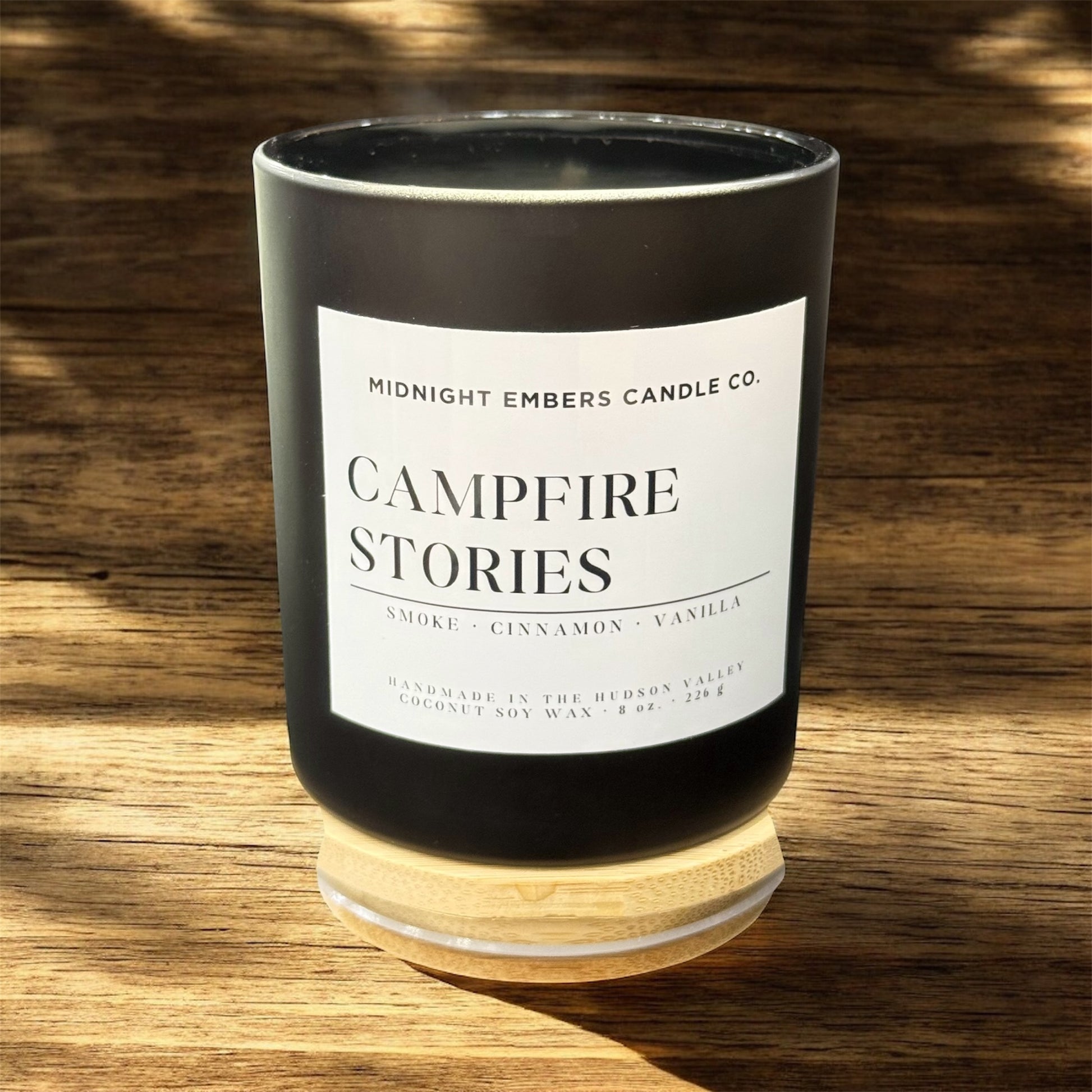 Candle with 'Campfire Stories' label on a wooden surface