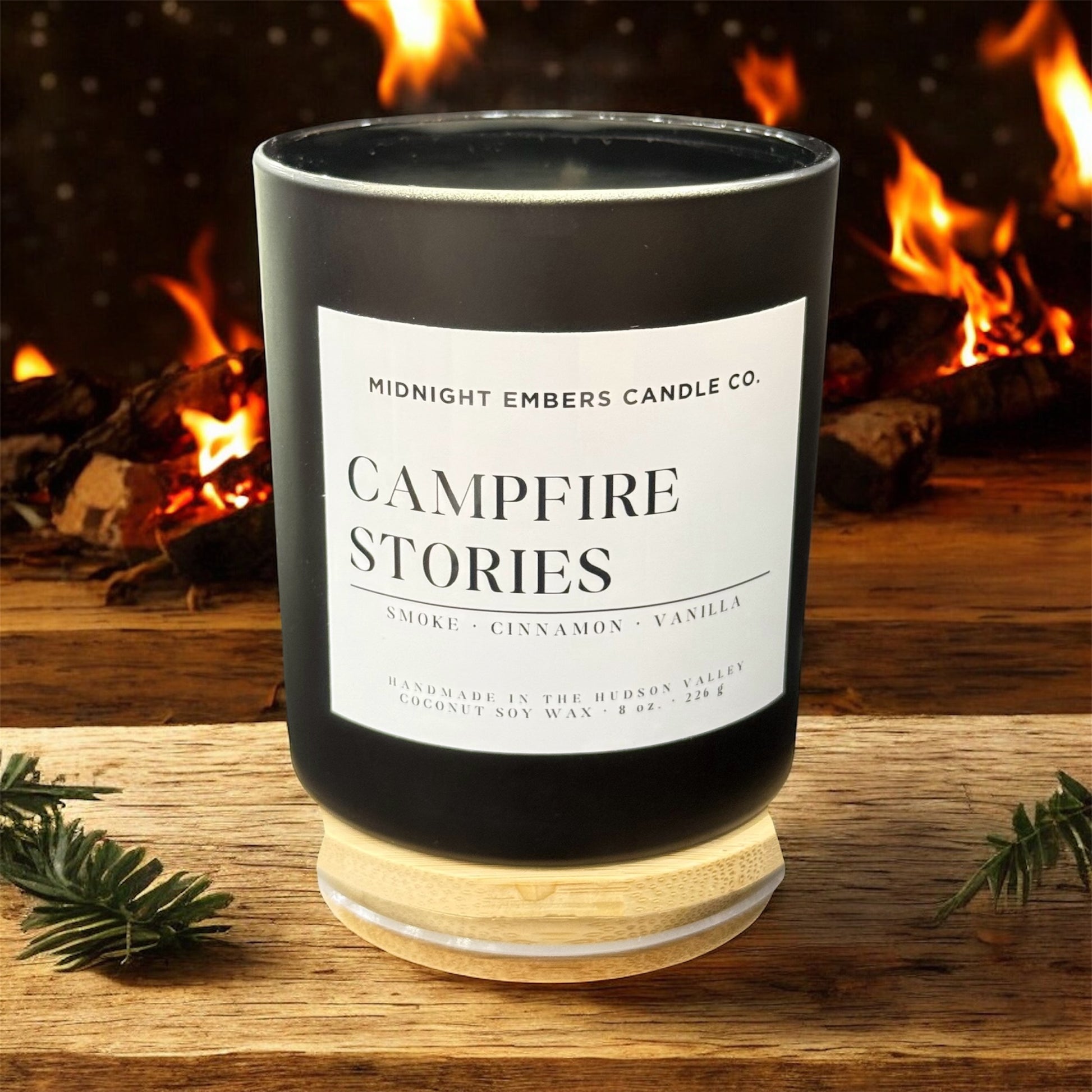 Candle labeled 'Campfire Stories' by Midnight Embers Candle Co. with a campfire in the background.