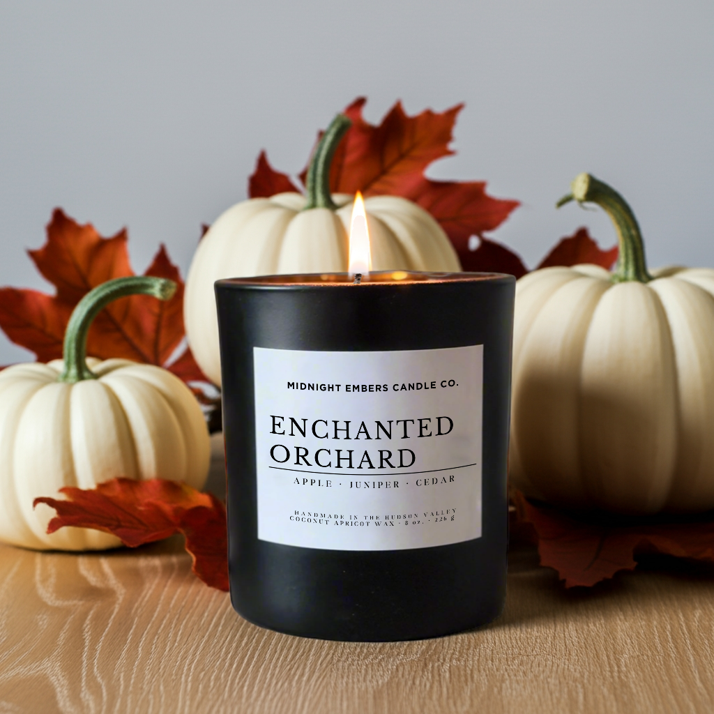 Candle labeled 'Enchanted Orchard' with pumpkins and leaves in the background