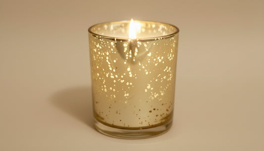 Candle in a decorative glass holder on a wooden surface with a blurred background