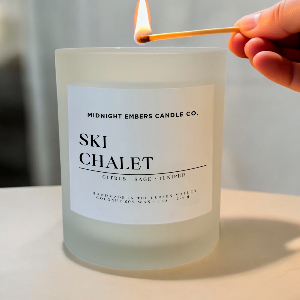 Candle labeled 'Ski Chalet' from Midnight Embers Candle Co. being lit with a match.